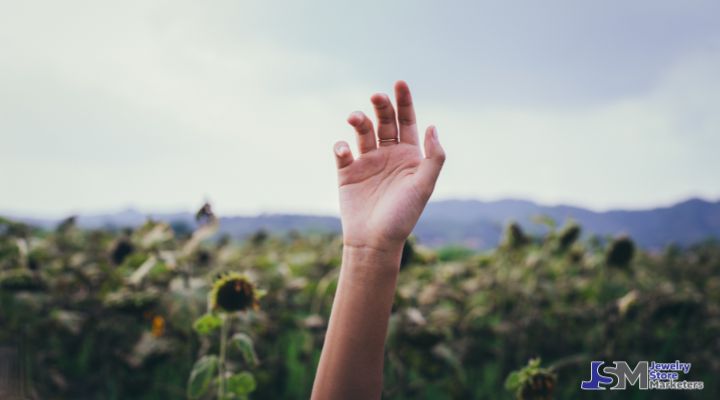 Raised hand wearing a ring in an outdoor setting